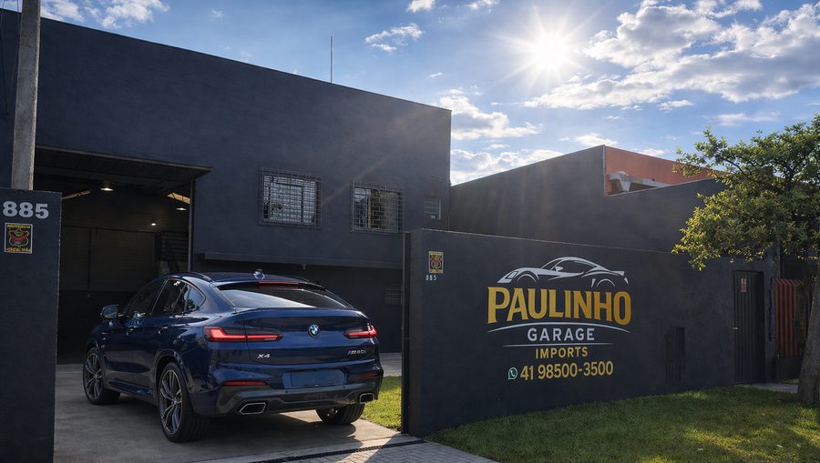 BMW X4 azul saindo da garagem da Paulinho Imports, na fachada da oficina