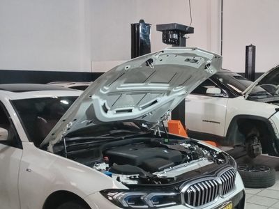 BMW Série 3 branco com o capô aberto durante o serviço