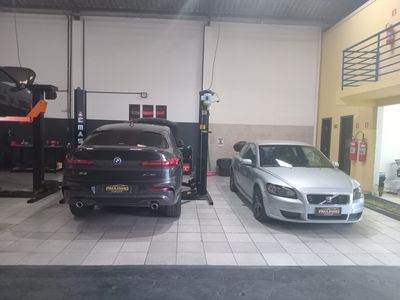 BMW X4 preto e Volvo C30 prata lado a lado no salão