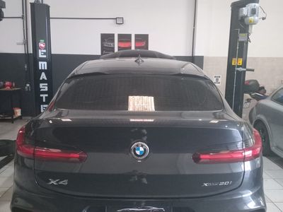 Traseira de BMW X4 preto entre dois elevadores