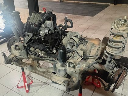 Motor, câmbio e conjunto de suspensão removidos e apoiados no chão da oficina