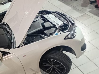 BMW Série 3 branco erguido no elevador, com a roda dianteira suspensa para avaliação de freios e suspensão